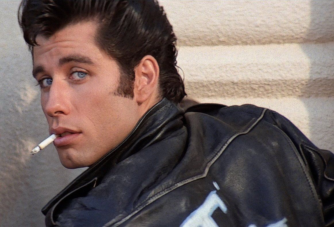 Does Travolta sing in Grease?